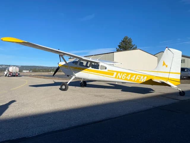 A full side view of a white and yellow Cessna 172 aircraft with registration N644FM parked on an airfield.