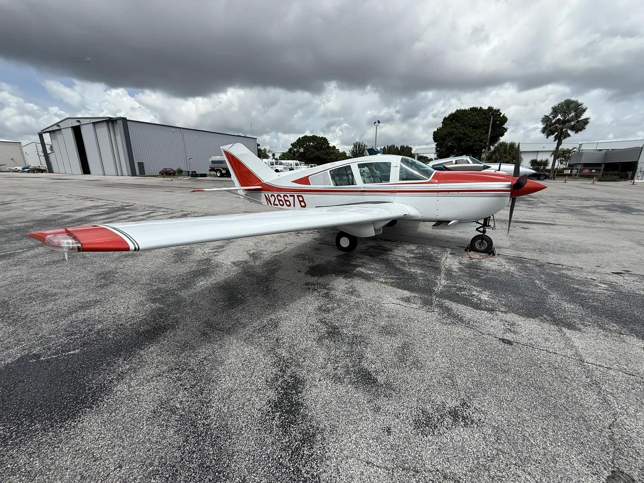 A full side view of the white and red single-engine aircraft, N2667B, parked on the tarmac.