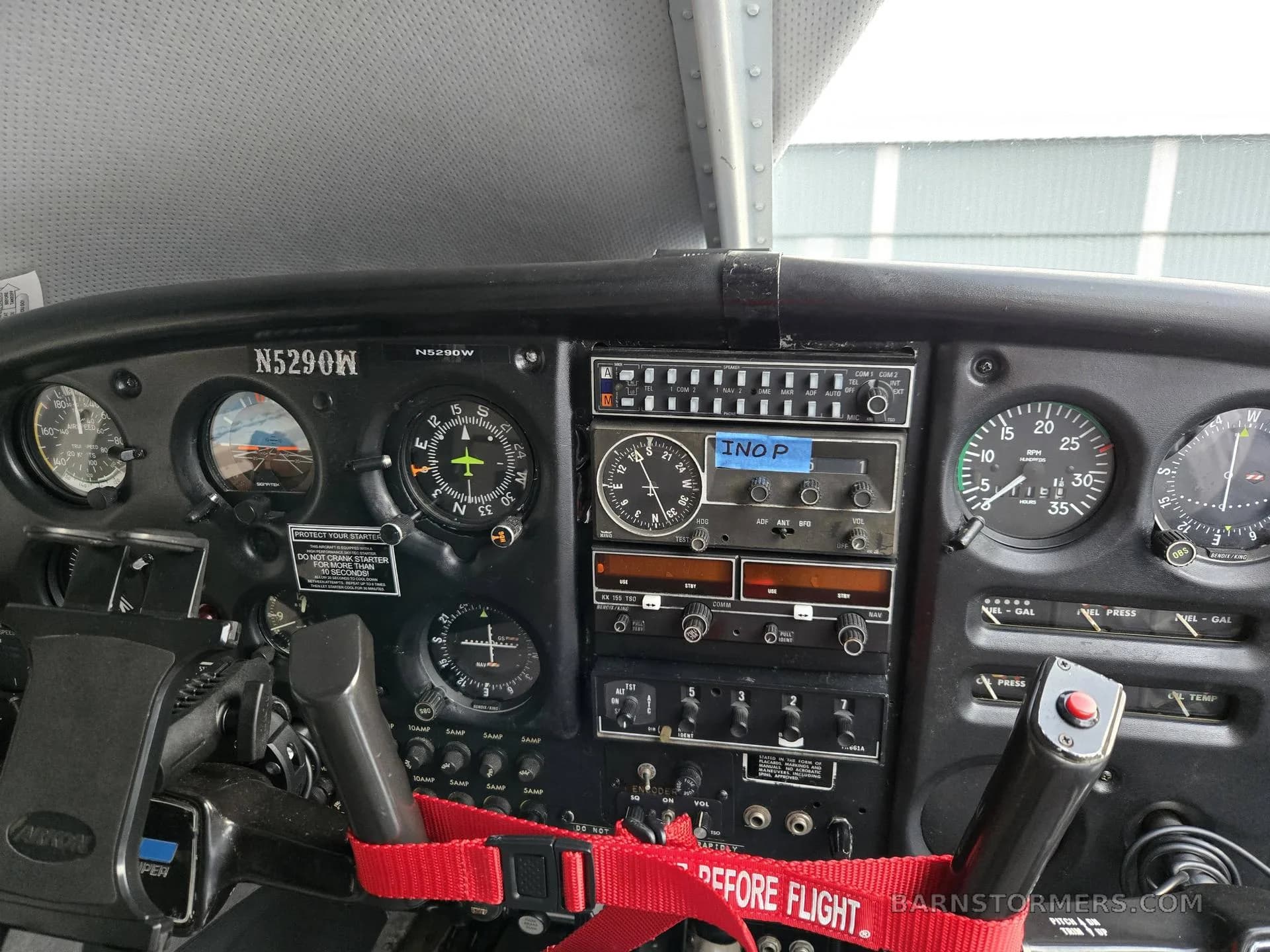 A close-up of the instrument panel in a small aircraft cockpit with gauges and radios.