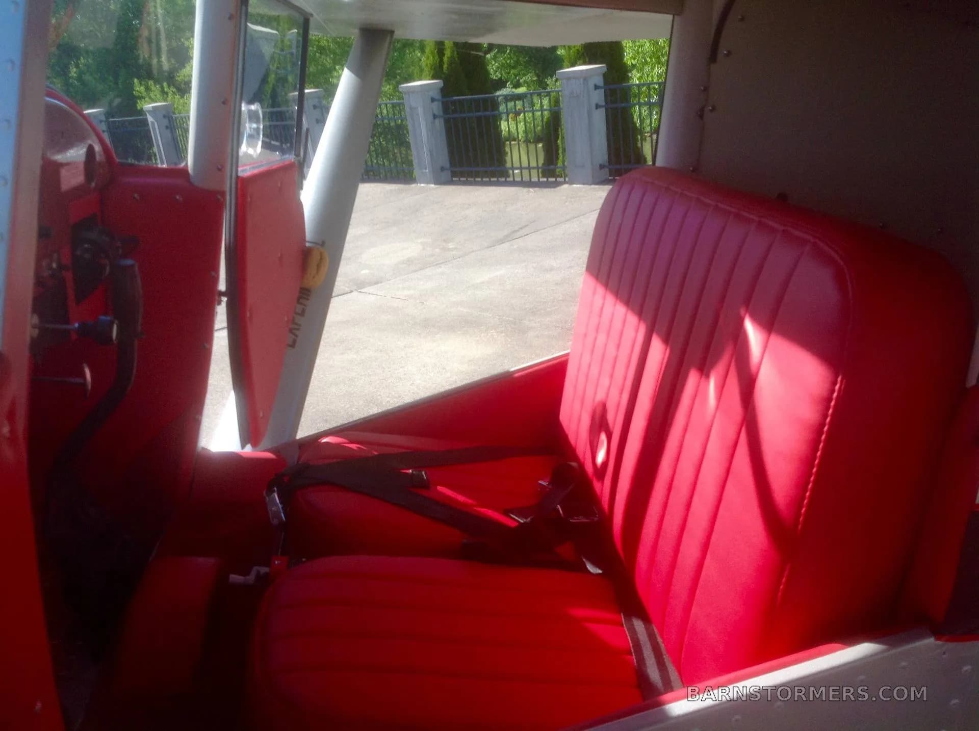 The red upholstered seats and interior of an aircraft cabin, with sunlight streaming in.