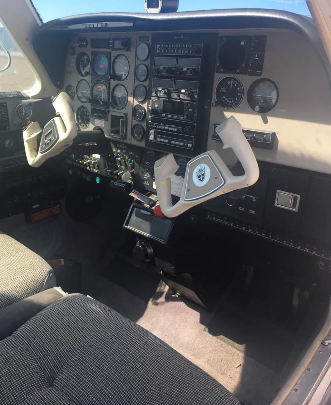 The cockpit of a Beechcraft Bonanza showing the instrument panel, two control yokes, and front seats.