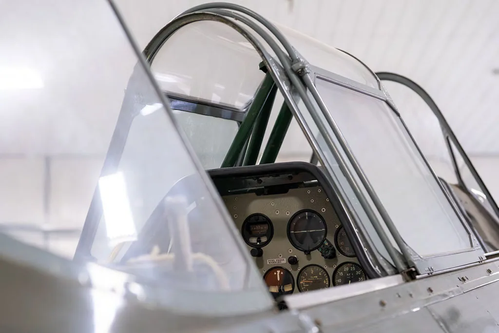 A close-up view of the instrument panel of a vintage aircraft, seen through the open canopy.