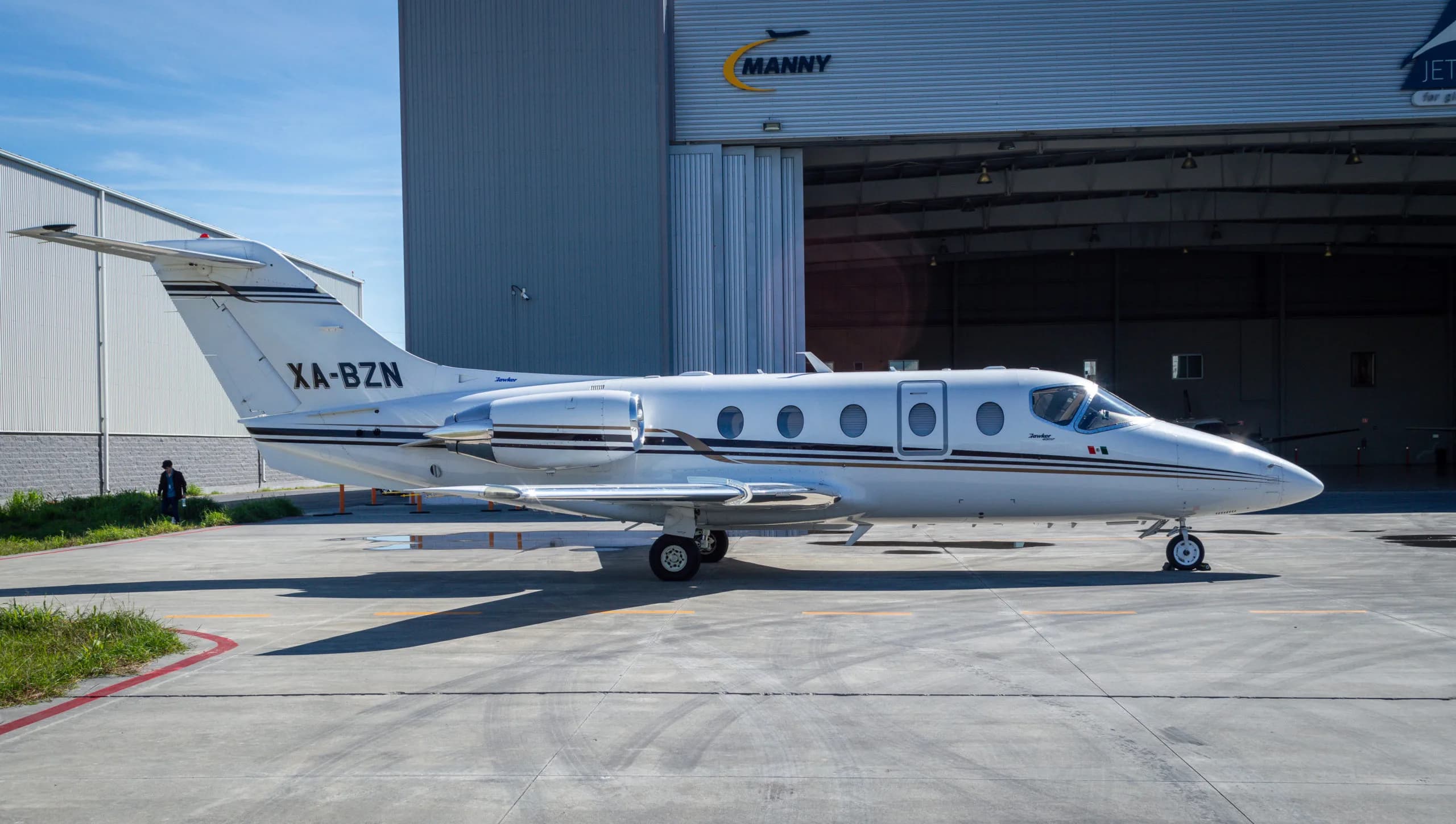 XA-BZN Learjet parked in front of a hangar with the Manny logo.