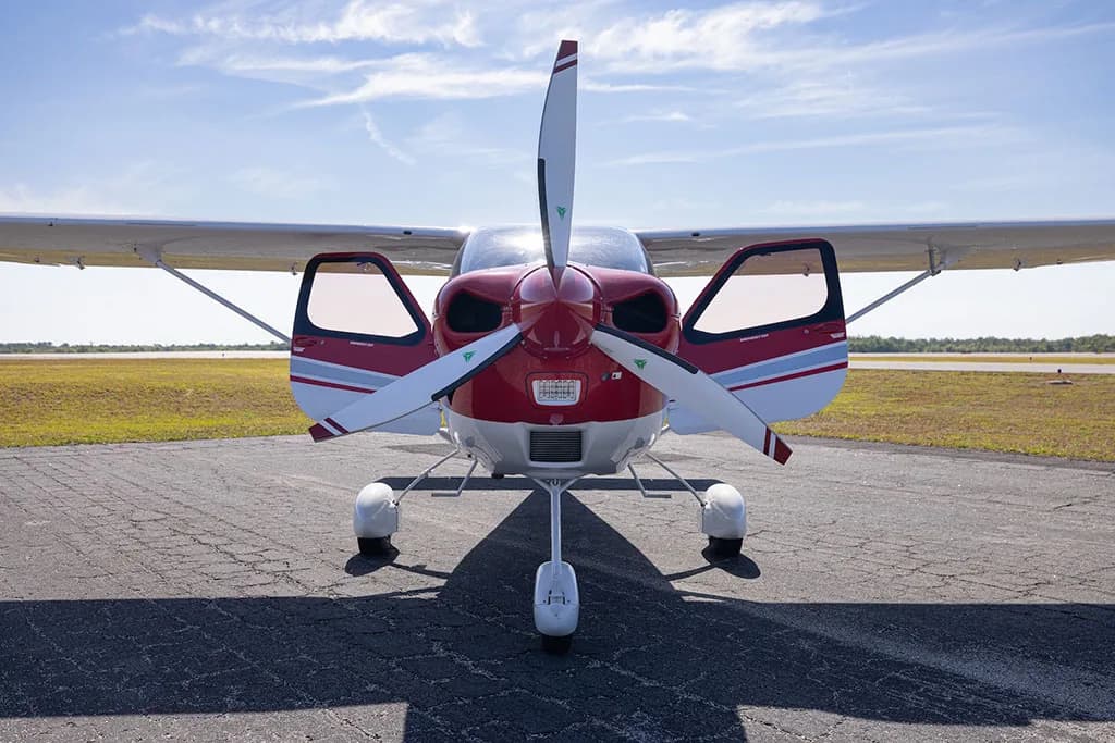 A head-on view of a red and white Tecnam P2010 aircraft with registration N598TC, with both doors open, on an airfield.