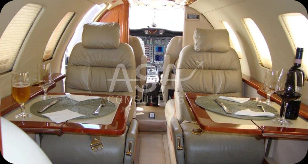 View of the aircraft cabin with tables set for a meal, looking towards the cockpit.