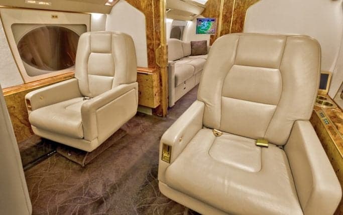 Aircraft cabin with seating and wood trim.
