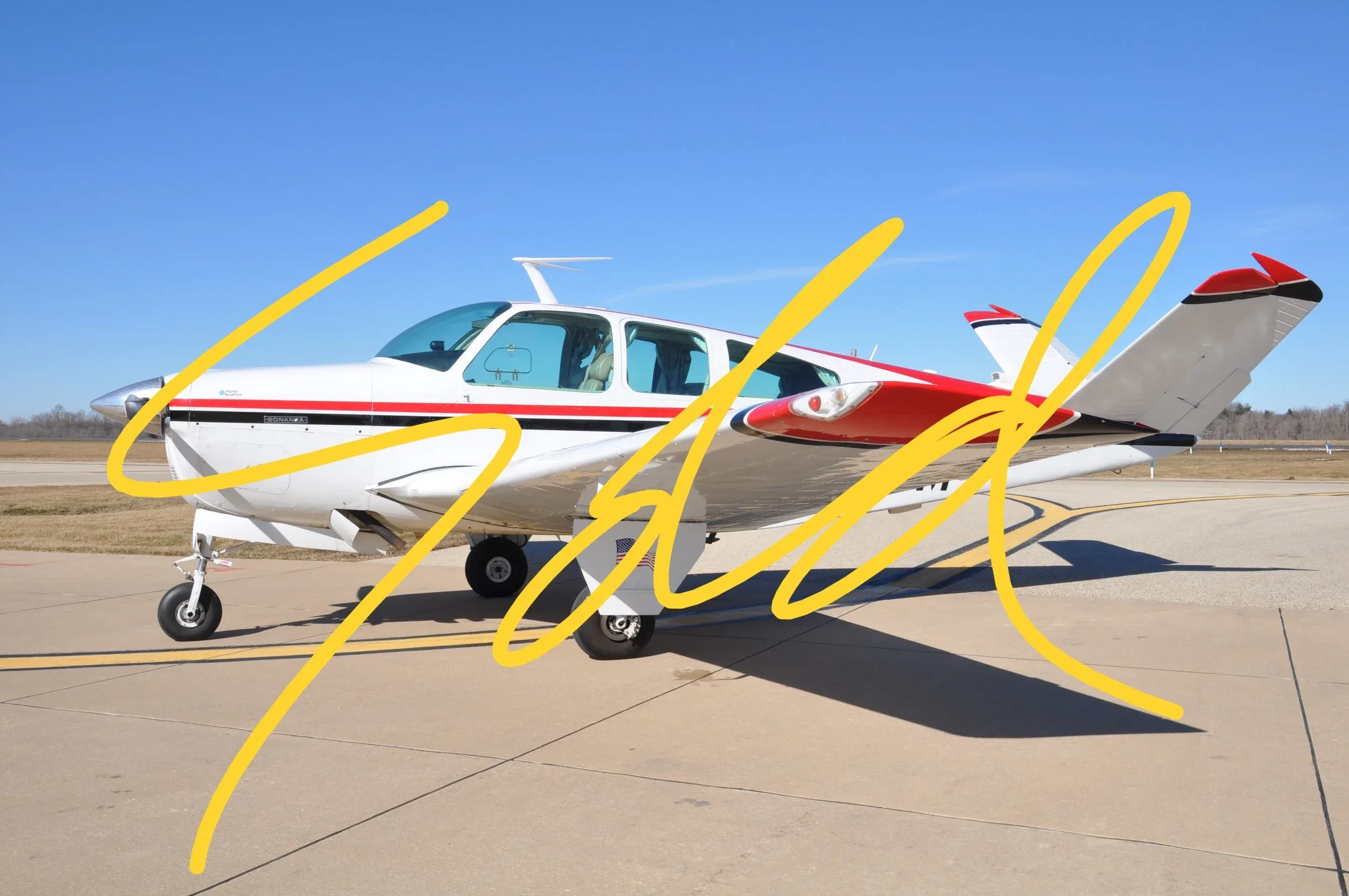 A white and red single-engine aircraft is parked on a tarmac under a clear blue sky.
