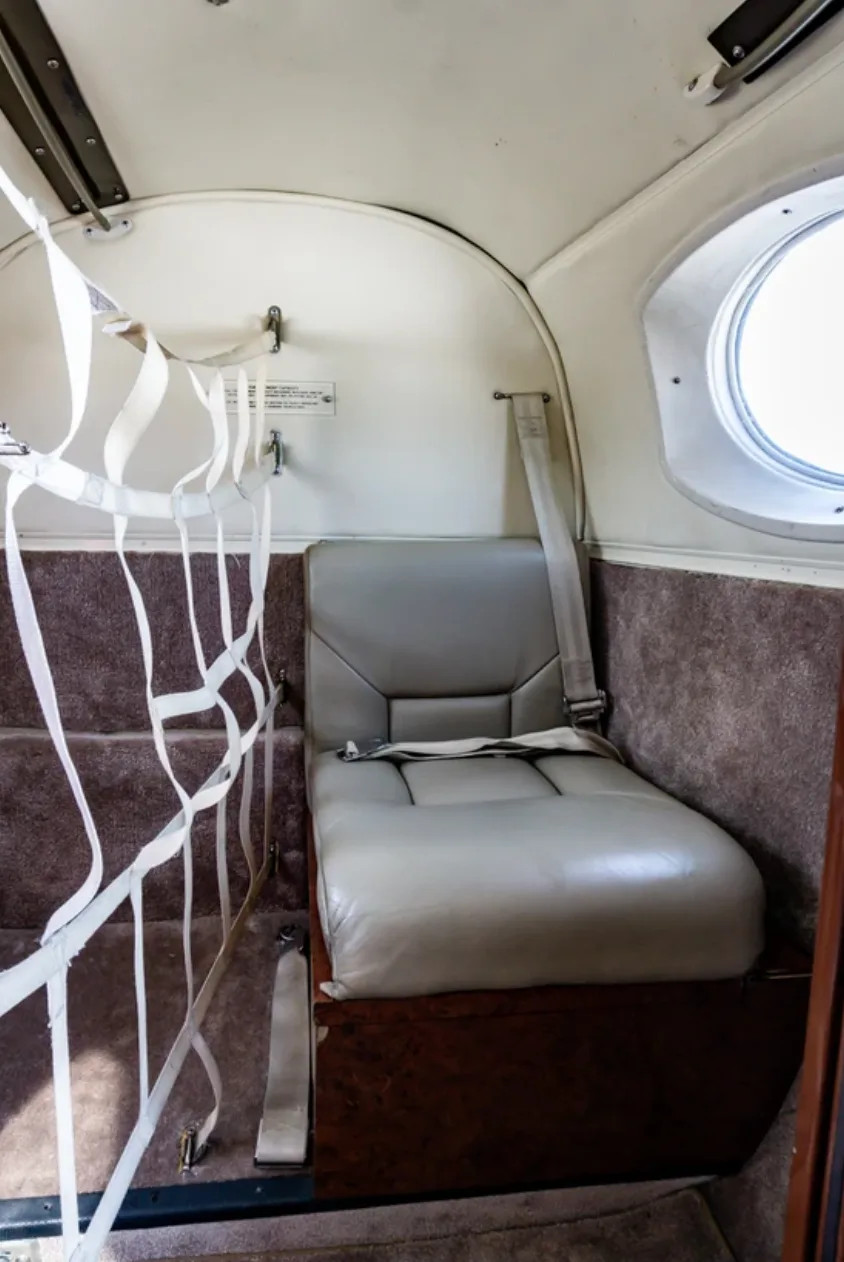 Close-up of a single seat in the Beechcraft King Air 200 cabin with a safety net.