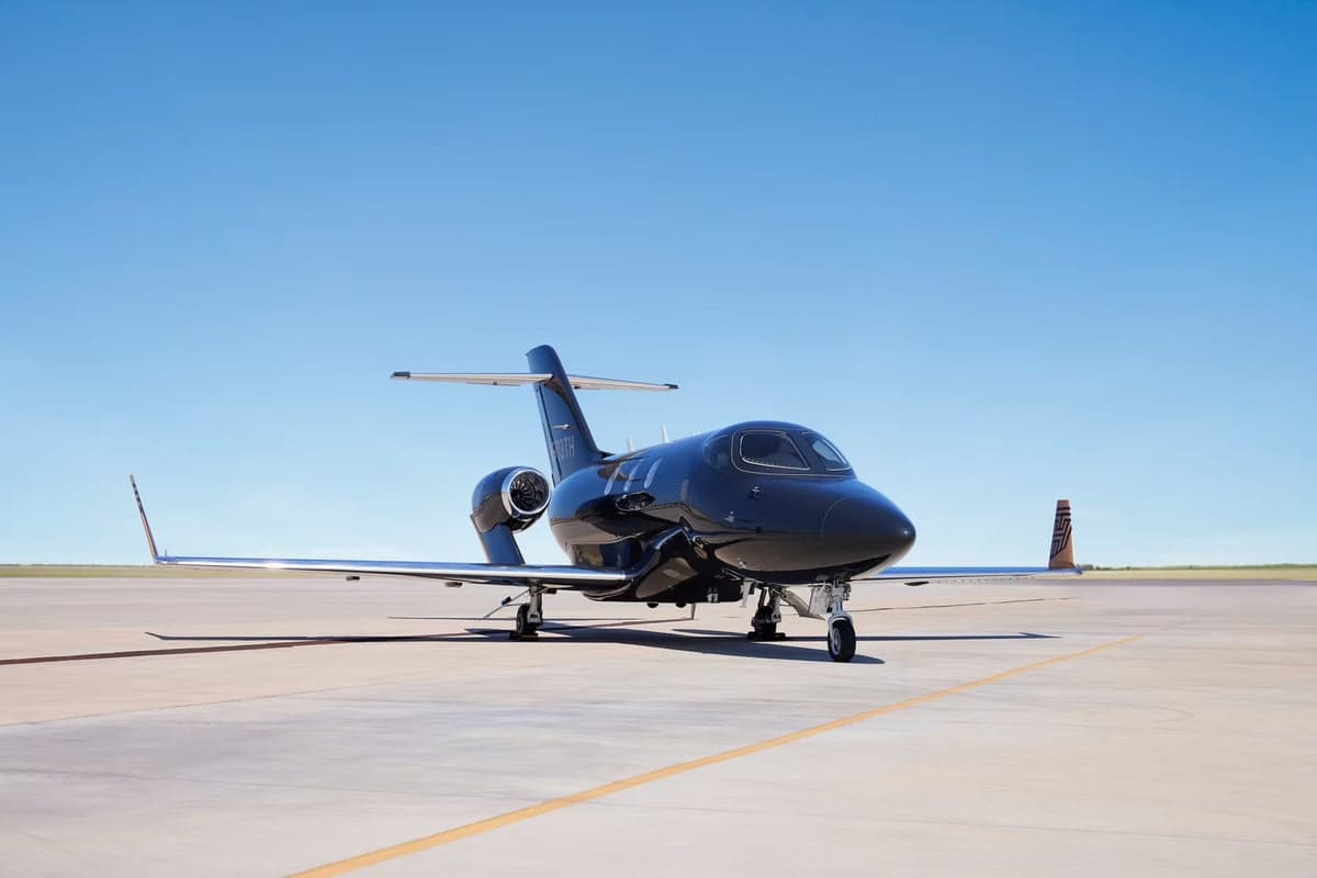 Side view of a dark-colored HondaJet on the tarmac.
