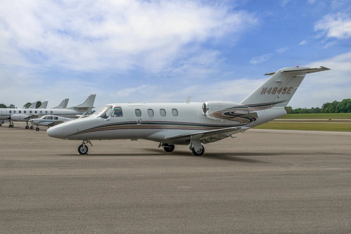 A Cessna Citation CJ1 on the tarmac with other aircraft in the background.