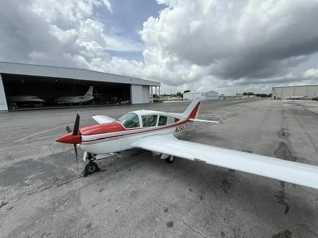 A wide-angle view of a white and red single-engine aircraft, N2667B, on an airport tarmac.