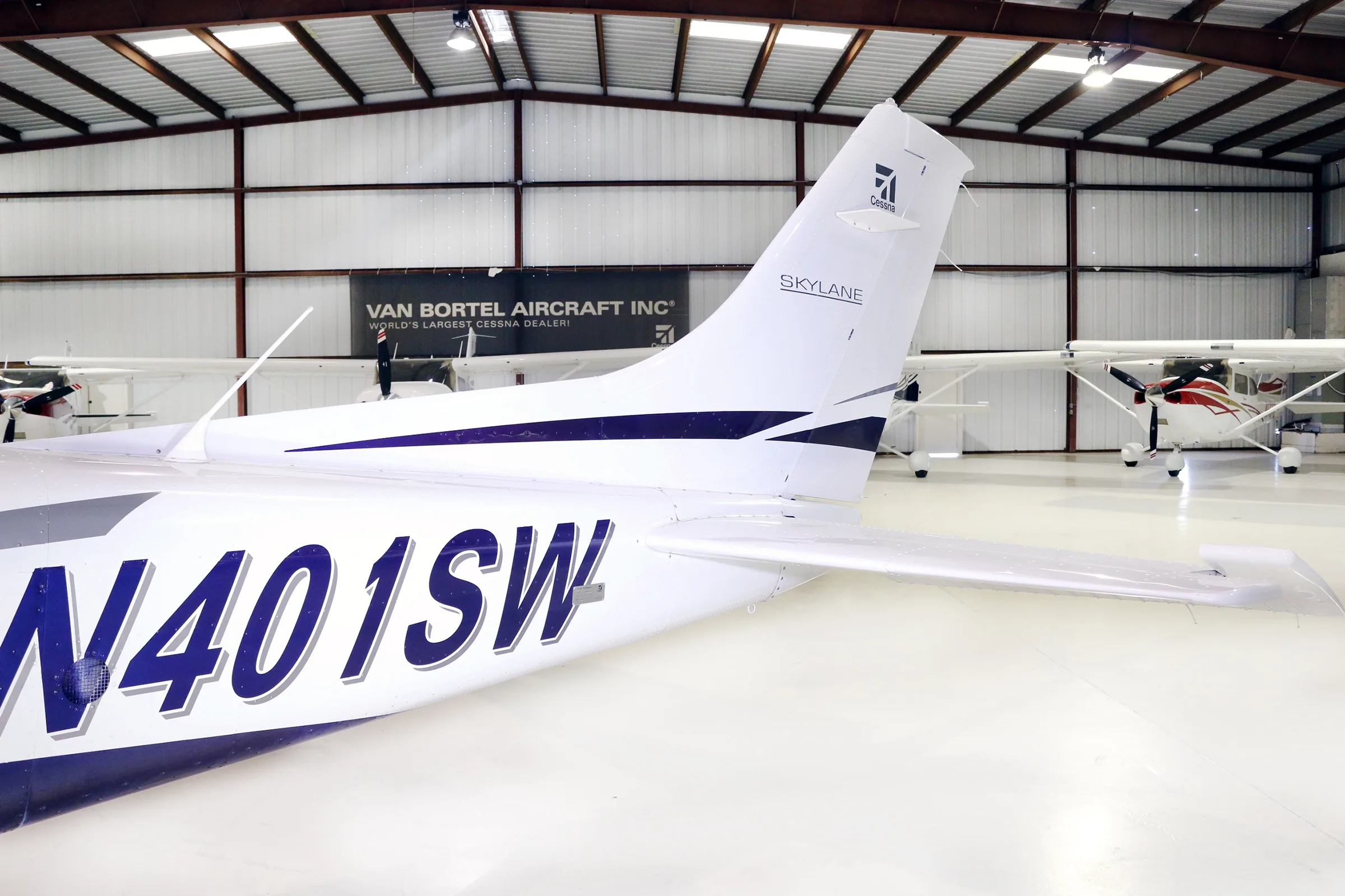 A close-up view of the tail section of a white and blue Cessna Skylane aircraft with registration N401SW.