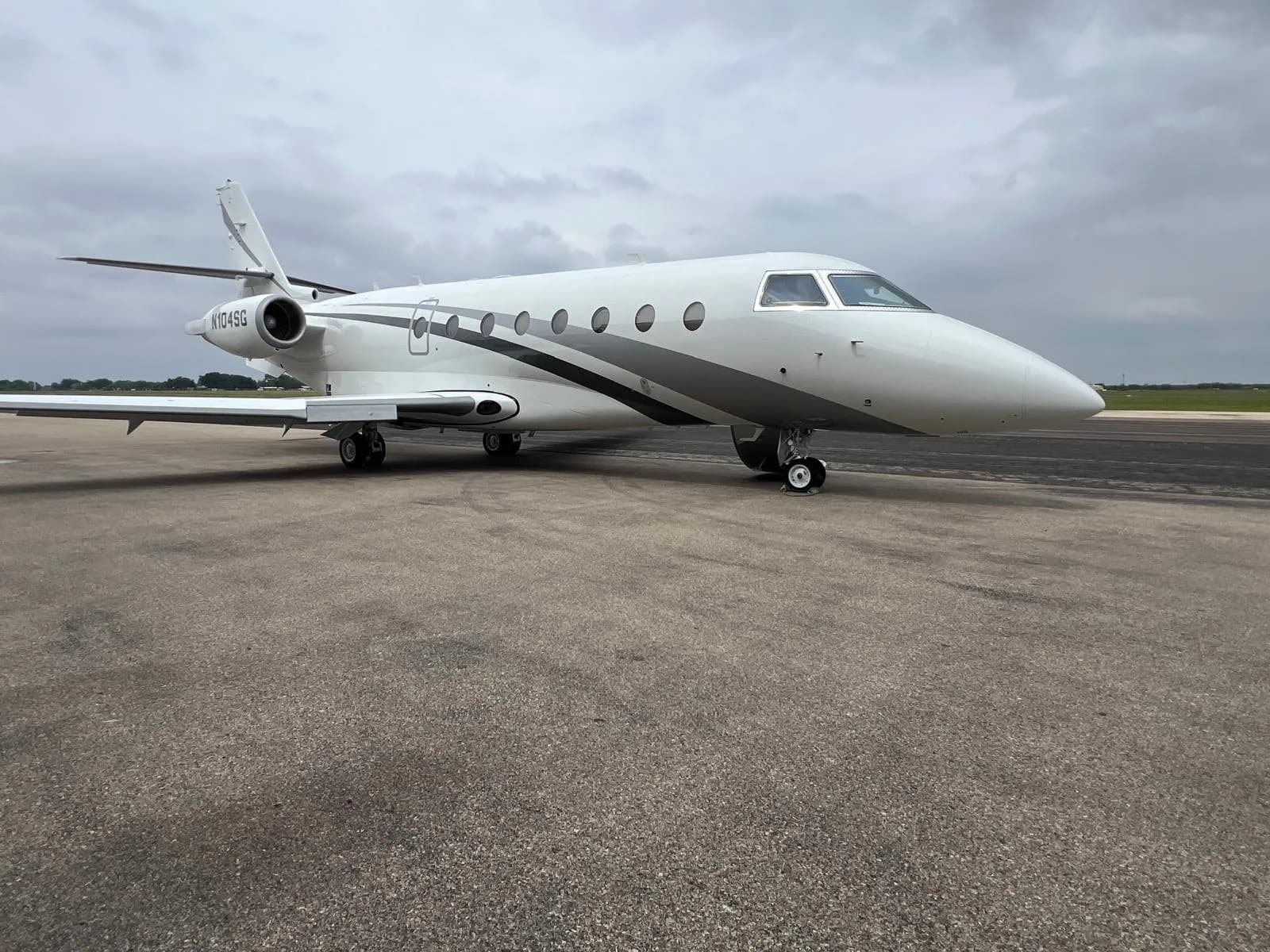 A white and gray jet with tail number N104SG sits on the tarmac.