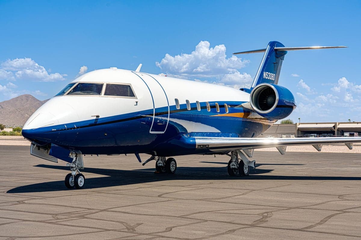 A blue and white Bombardier Challenger 300 on the tarmac.