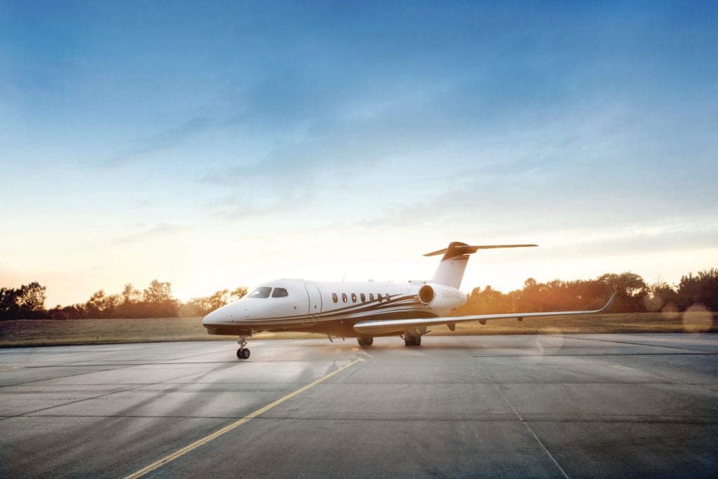 A Citation Longitude jet parked on the tarmac at sunset.