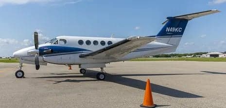 Side view of a white and blue King Air aircraft on the tarmac.