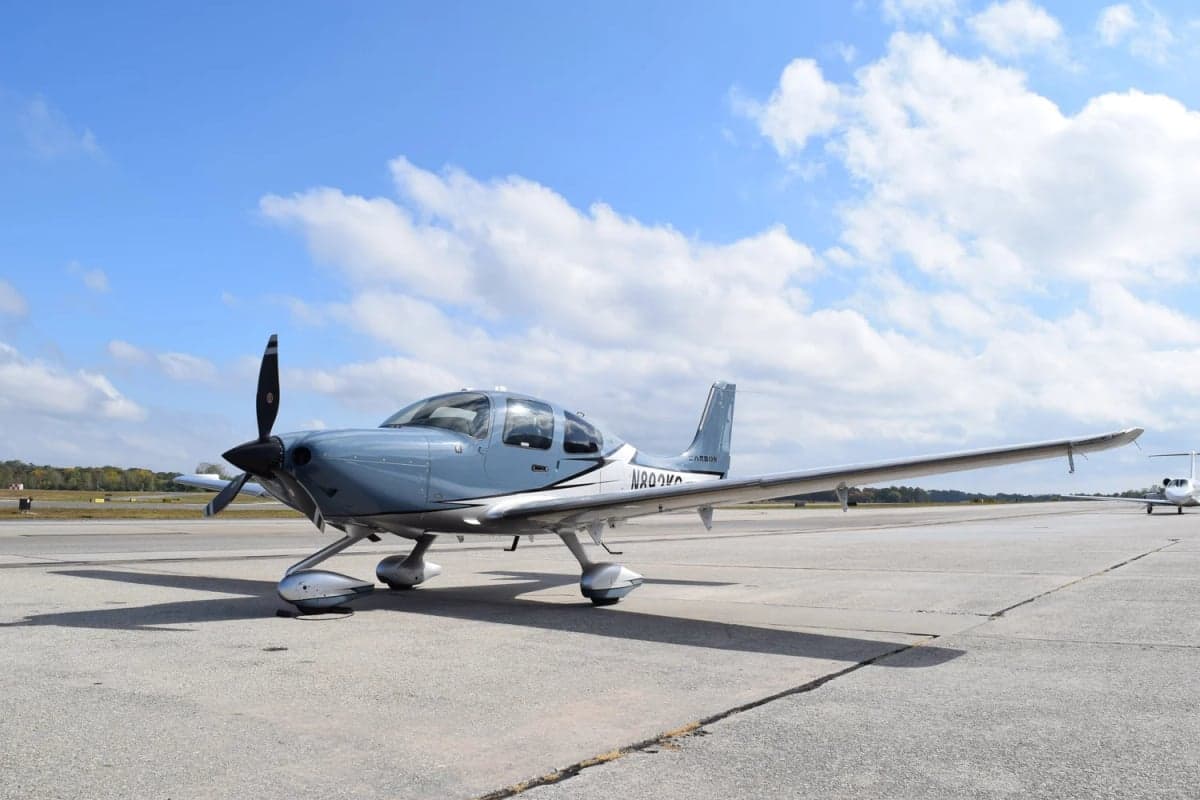A Cirrus SR22T aircraft with a blue and silver paint scheme is parked on the tarmac.