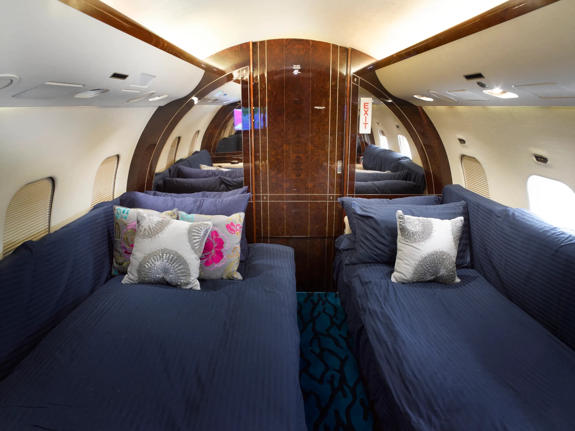 Aft cabin of the aircraft with blue fabric seats and decorative pillows.
