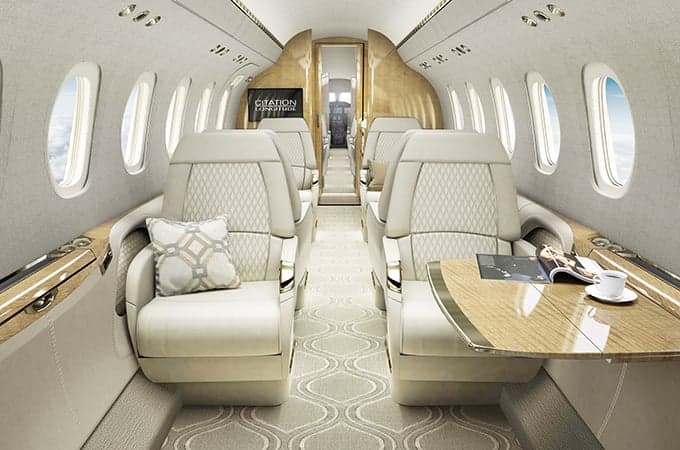 The interior of a Citation Longitude jet with cream-colored leather seats and wood accents.