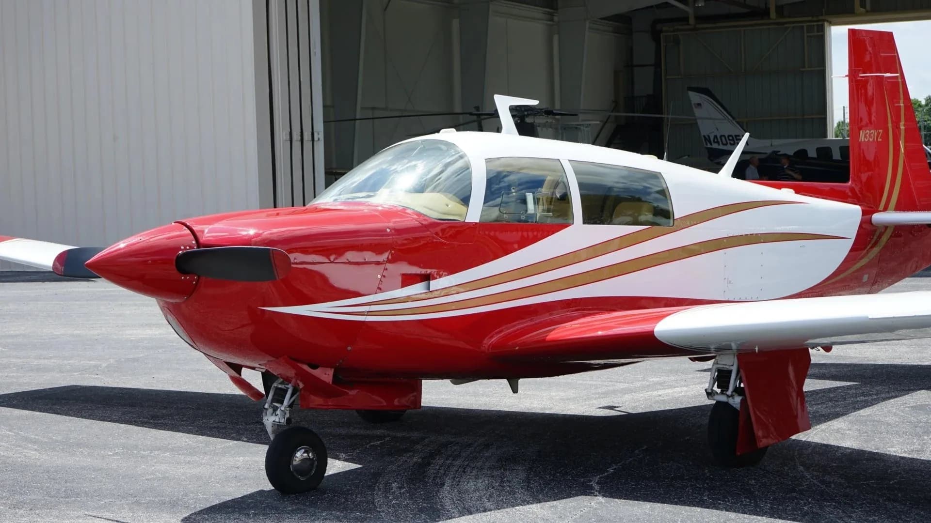 A close-up side view of the red and white aircraft, N33YZ, highlighting the cockpit and front fuselage.
