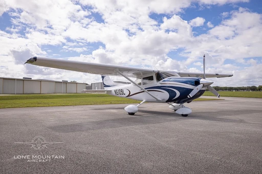 A front three-quarter view of the white and blue Cessna 182 Skylane aircraft, N510SL, parked on an airfield.