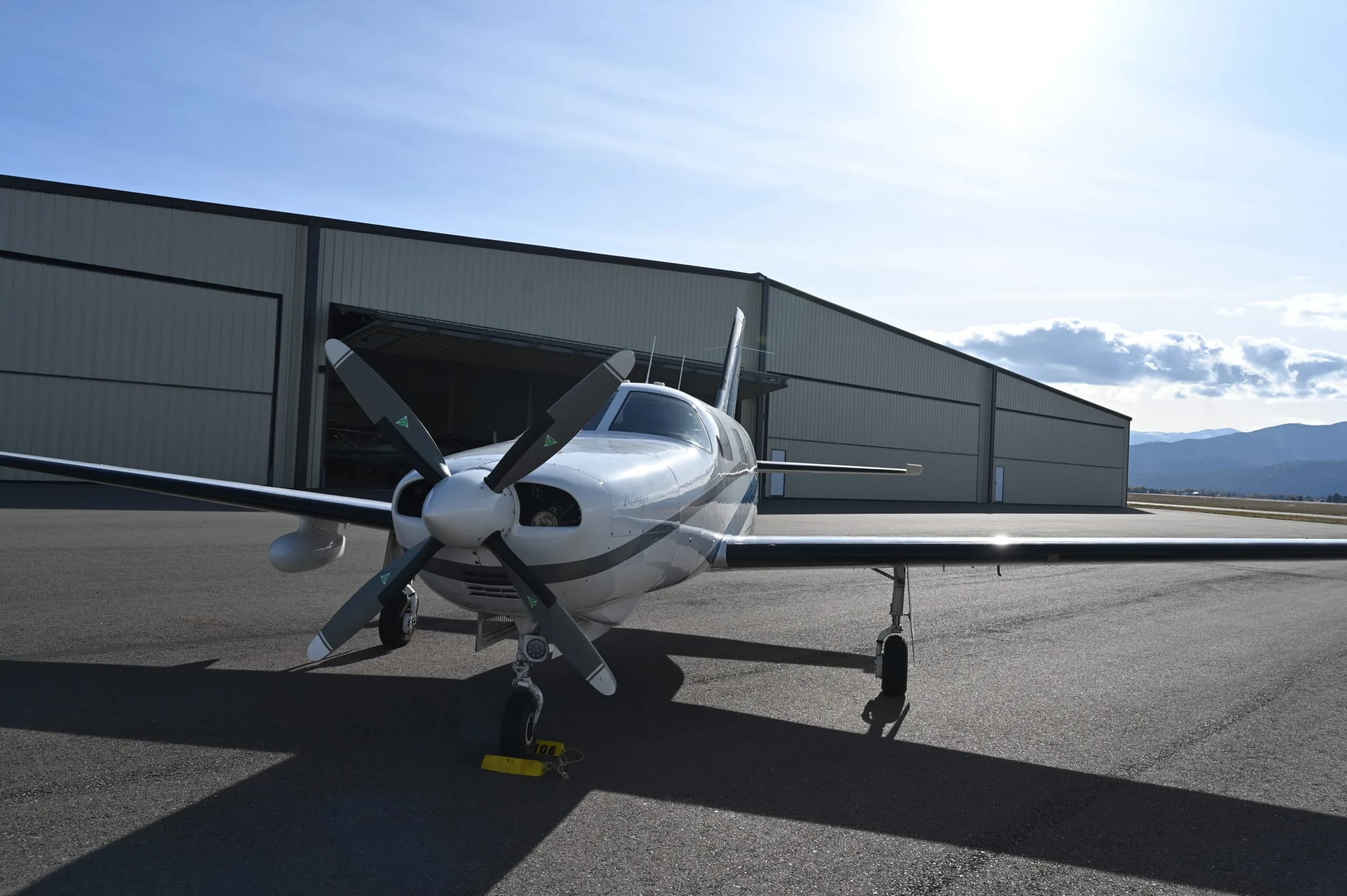 Front view of a Piper Mirage parked on the tarmac in front of a hangar.
