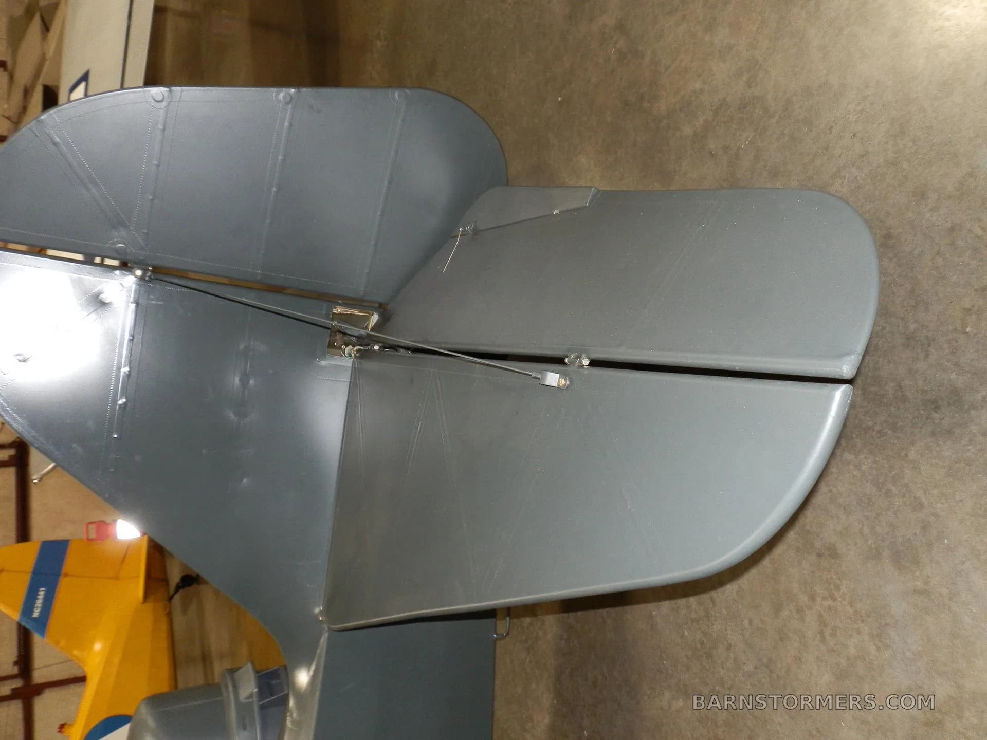 A close-up view of the dark grey tail section, showing the rudder and elevators of a taildragger aircraft.
