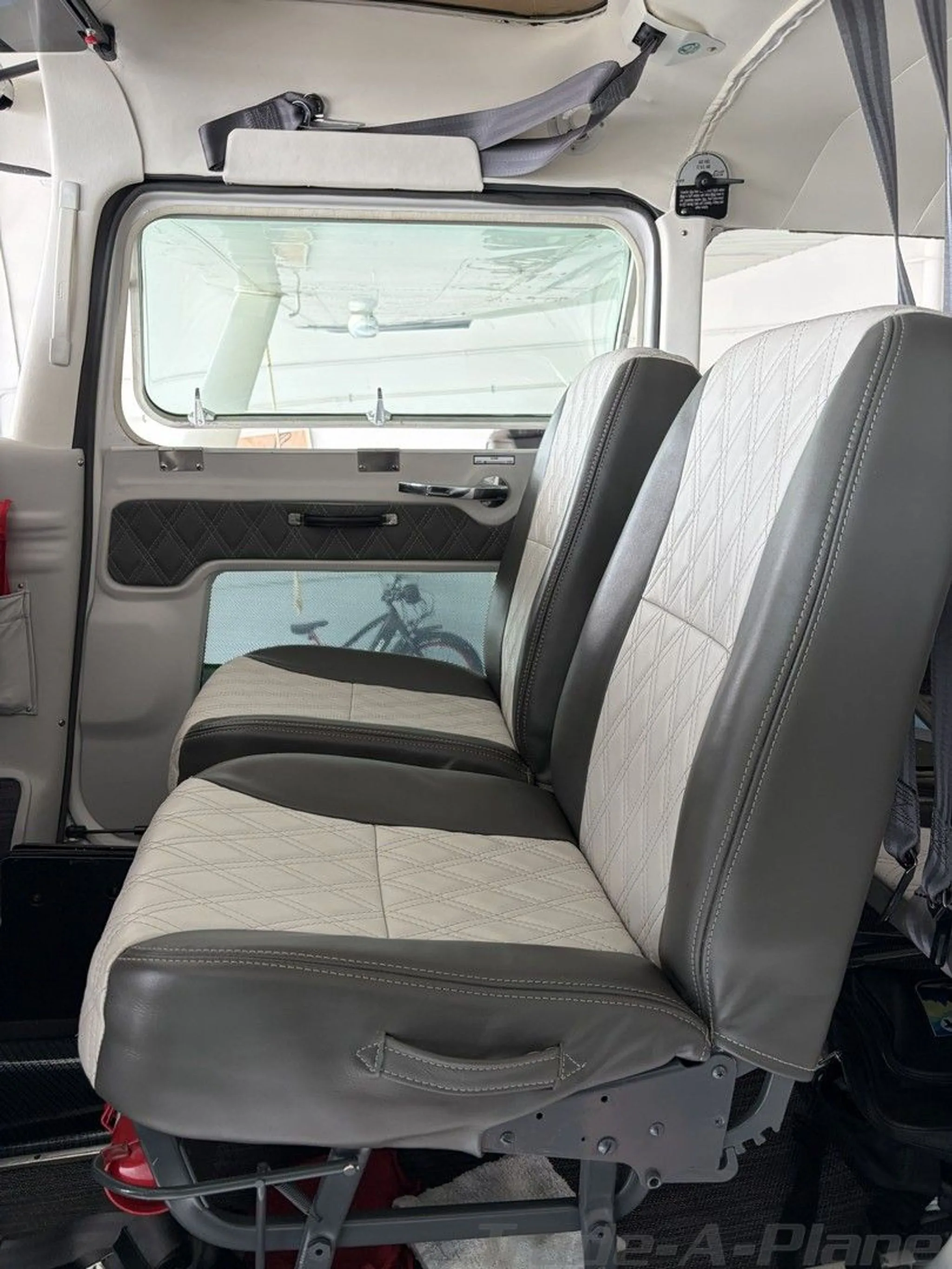 The rear cabin seats of the aircraft, upholstered in two-tone grey and white with a diamond stitch pattern.