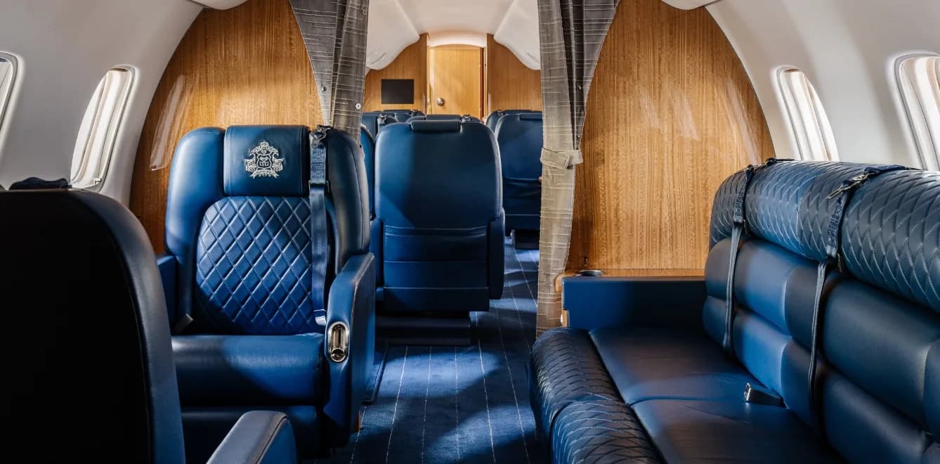View of the aircraft cabin with blue leather seats and wood paneling.