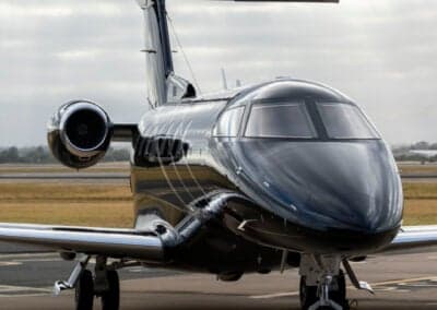 Close-up side view of a black Pilatus PC-24 jet on the tarmac.