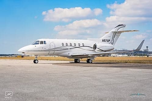 A white jet aircraft with registration N97XP parked on the tarmac.