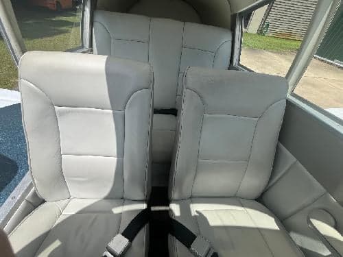 The light gray leather interior of the Piper Cherokee 180 aircraft, showing two front seats and a rear bench seat.