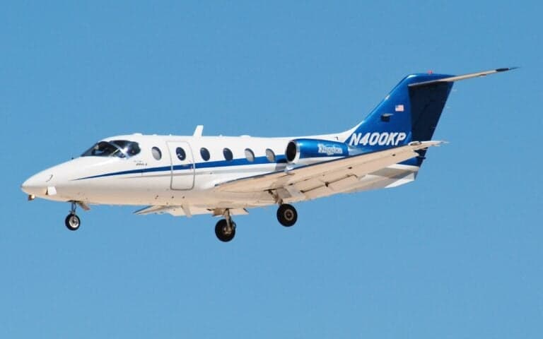 A white and blue jet with tail number N86LF landing on a runway.