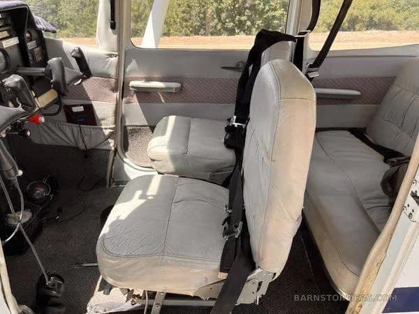 The light gray leather front and rear passenger seats of a small aircraft cabin, viewed from the side.