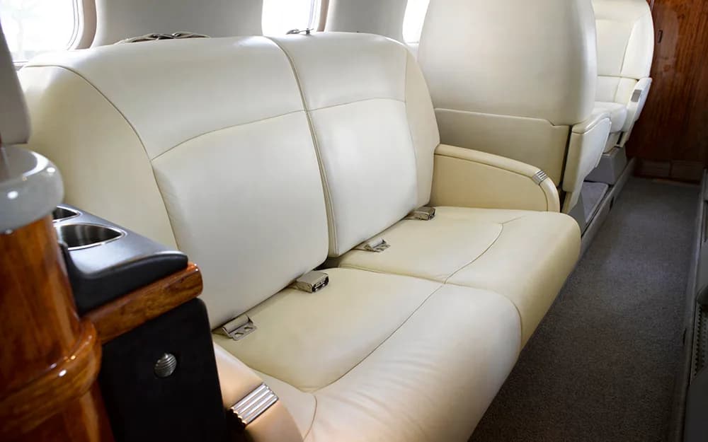 A close-up view of two cream leather seats in the private jet cabin.