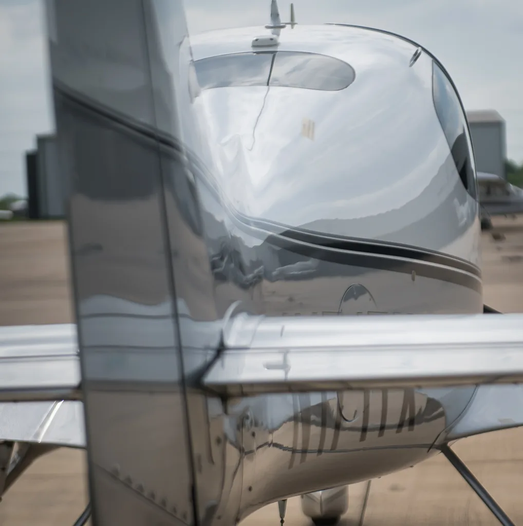 A close-up, slightly blurred view of the rear fuselage and tail of the Cirrus SR22T, showing reflections on its shiny surface.