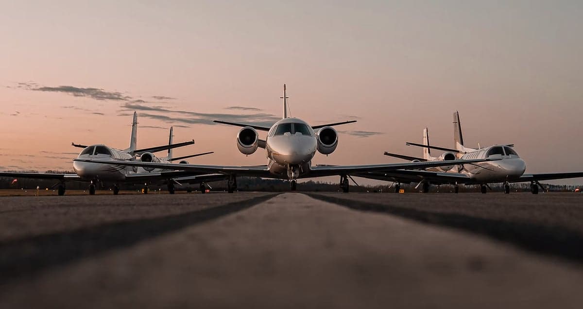 Three Cessna Citation CJ4 aircraft lined up on a runway at sunset.