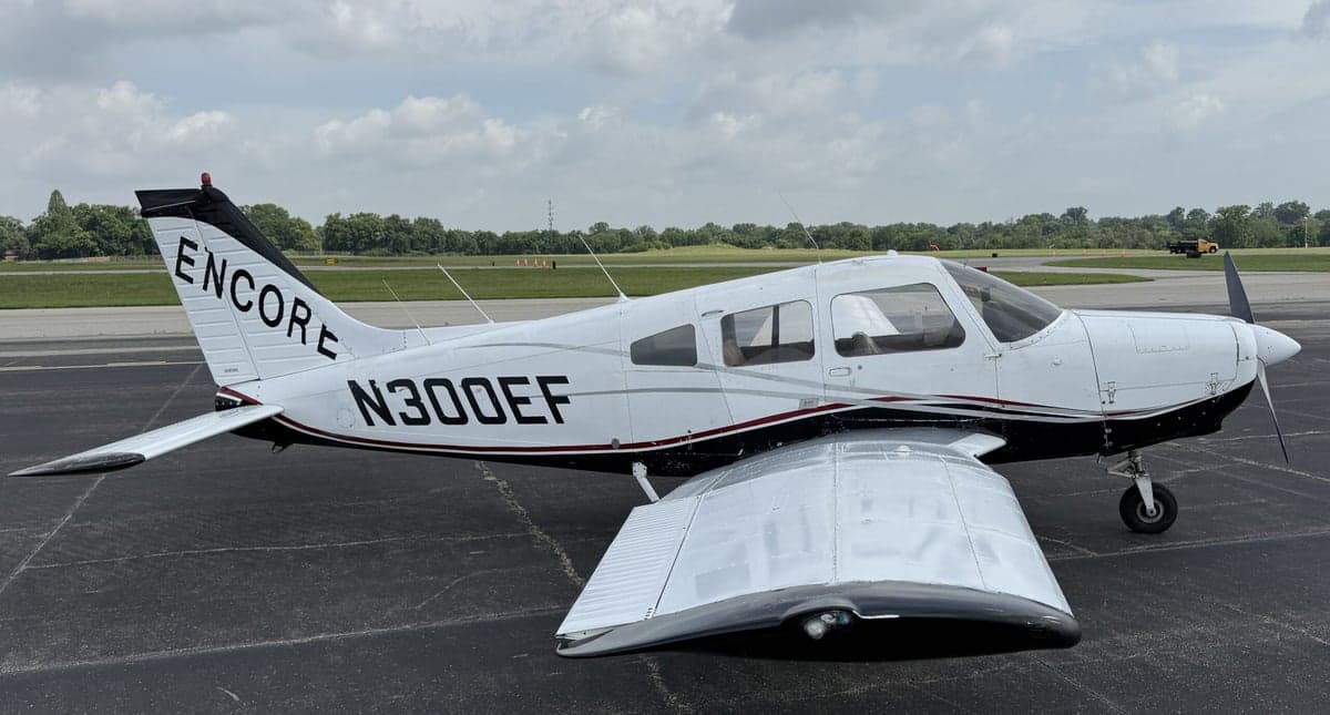 Side view of a white and black Piper PA-28-181 Archer II with registration N300EF on the tarmac.