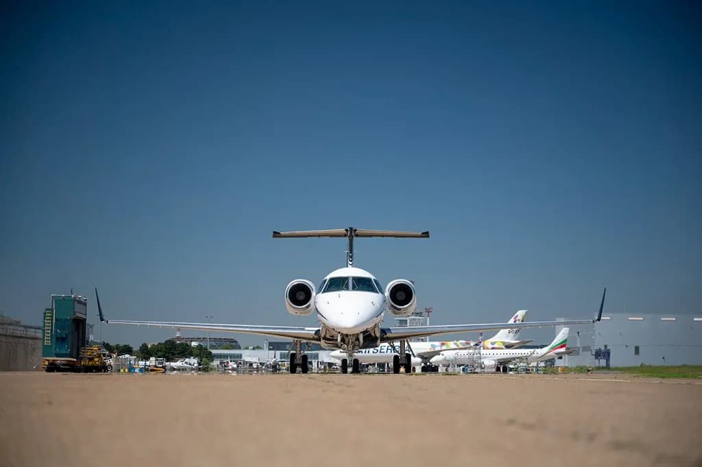 A head-on view of a white and black Embraer Legacy 600 business jet with registration YU-PAA on a tarmac.