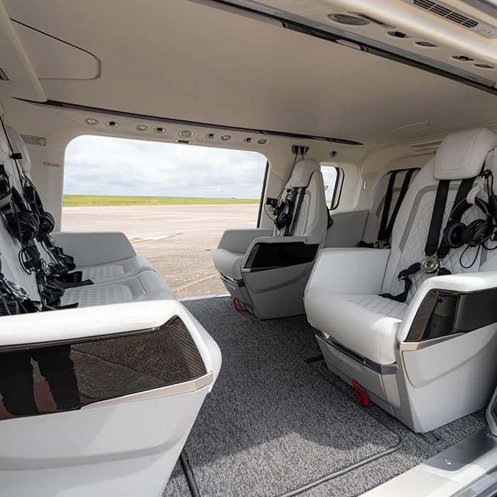 The helicopter's interior features white leather seats and a gray carpet.
