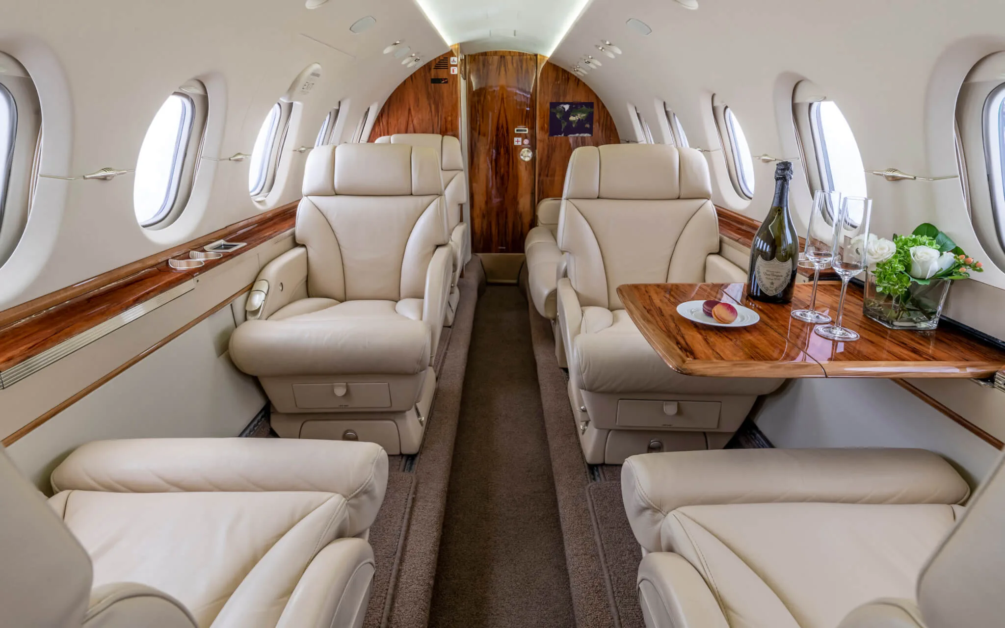 Interior view of the aircraft cabin with leather seats and a table set with wine.