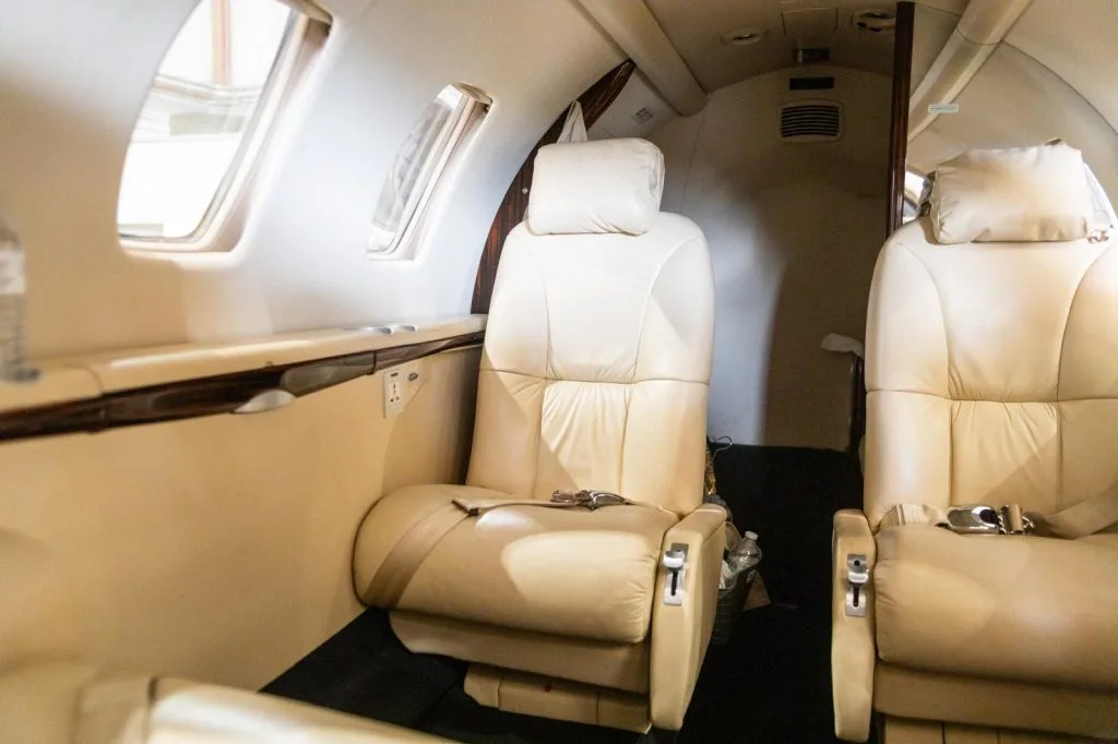 A side view of the beige leather seats in the interior cabin of a business jet.