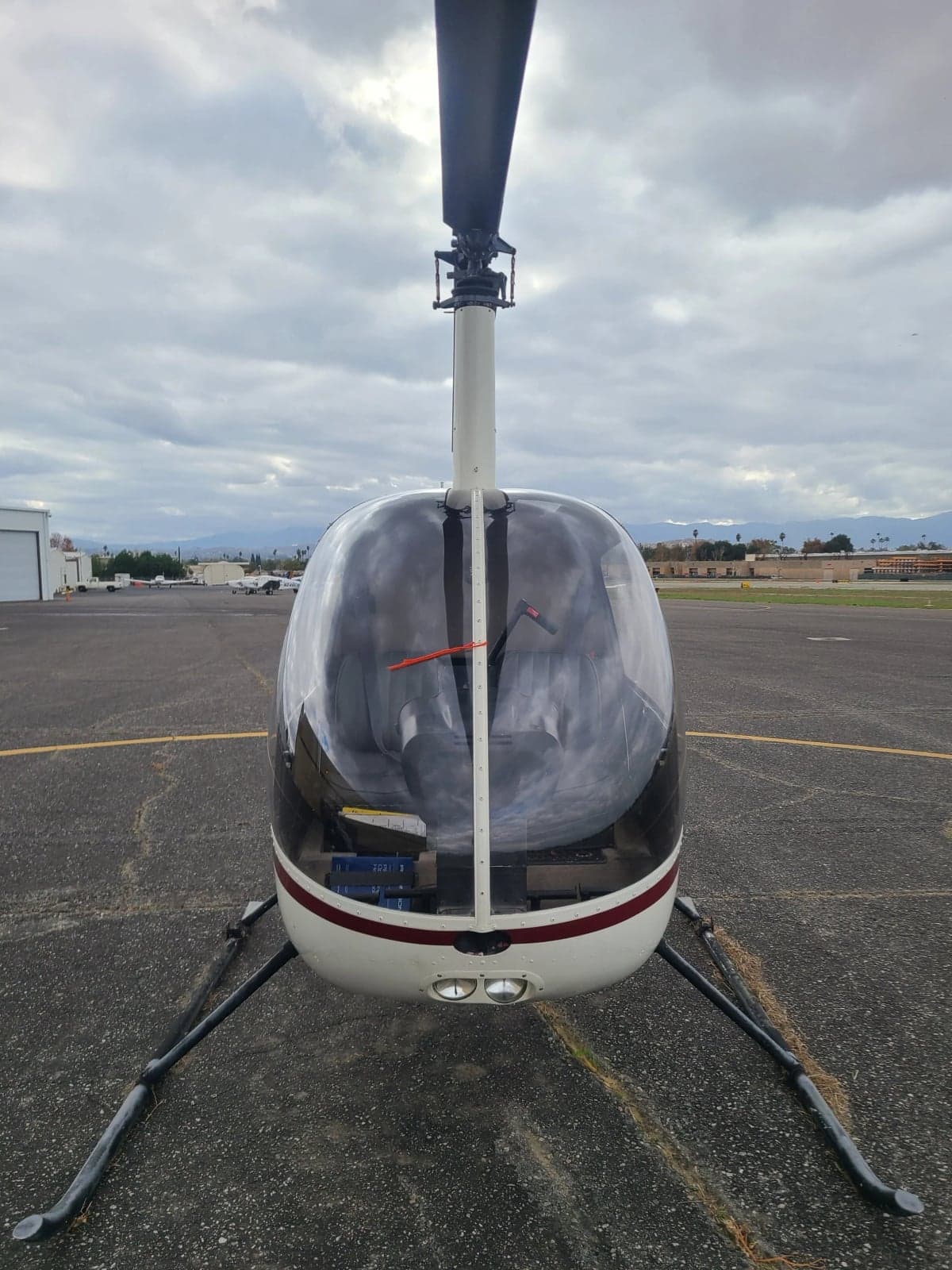 A front view of a white and red Robinson R22 Beta helicopter with registration N8311A, parked on an airport apron.