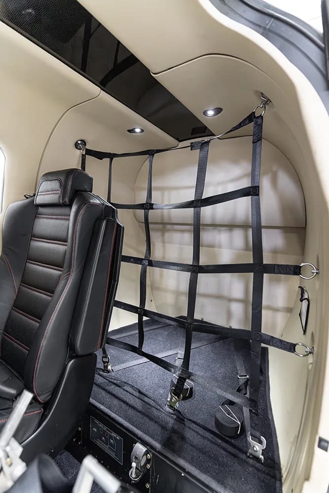 A view of the rear cargo area of a small aircraft, secured with a black netting.
