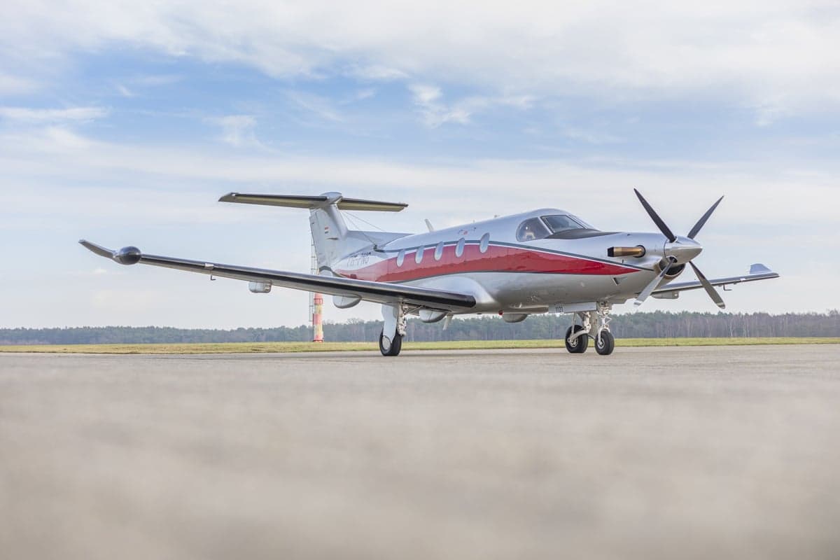 A Pilatus PC-12 aircraft with a silver and red paint scheme, registration PH-PNG, parked on the tarmac.