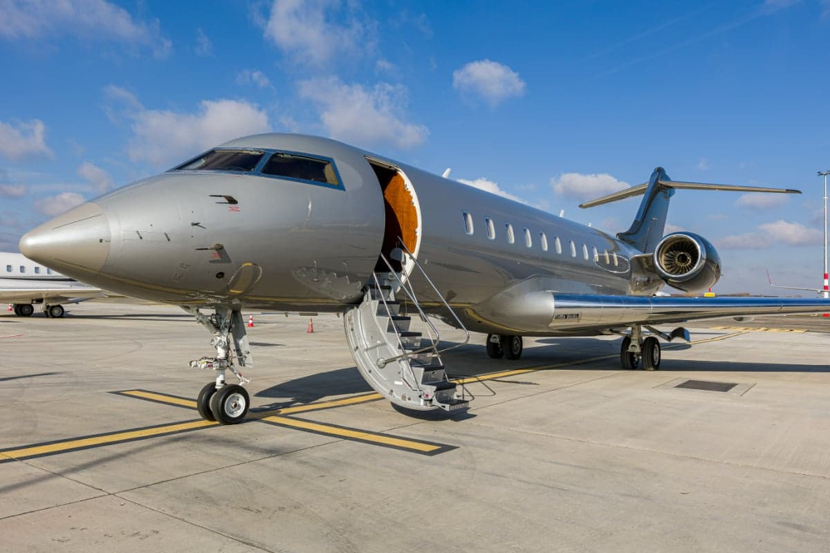 The Bombardier Global 5000 aircraft 9H-ARE is parked on the tarmac with the airstair door open.