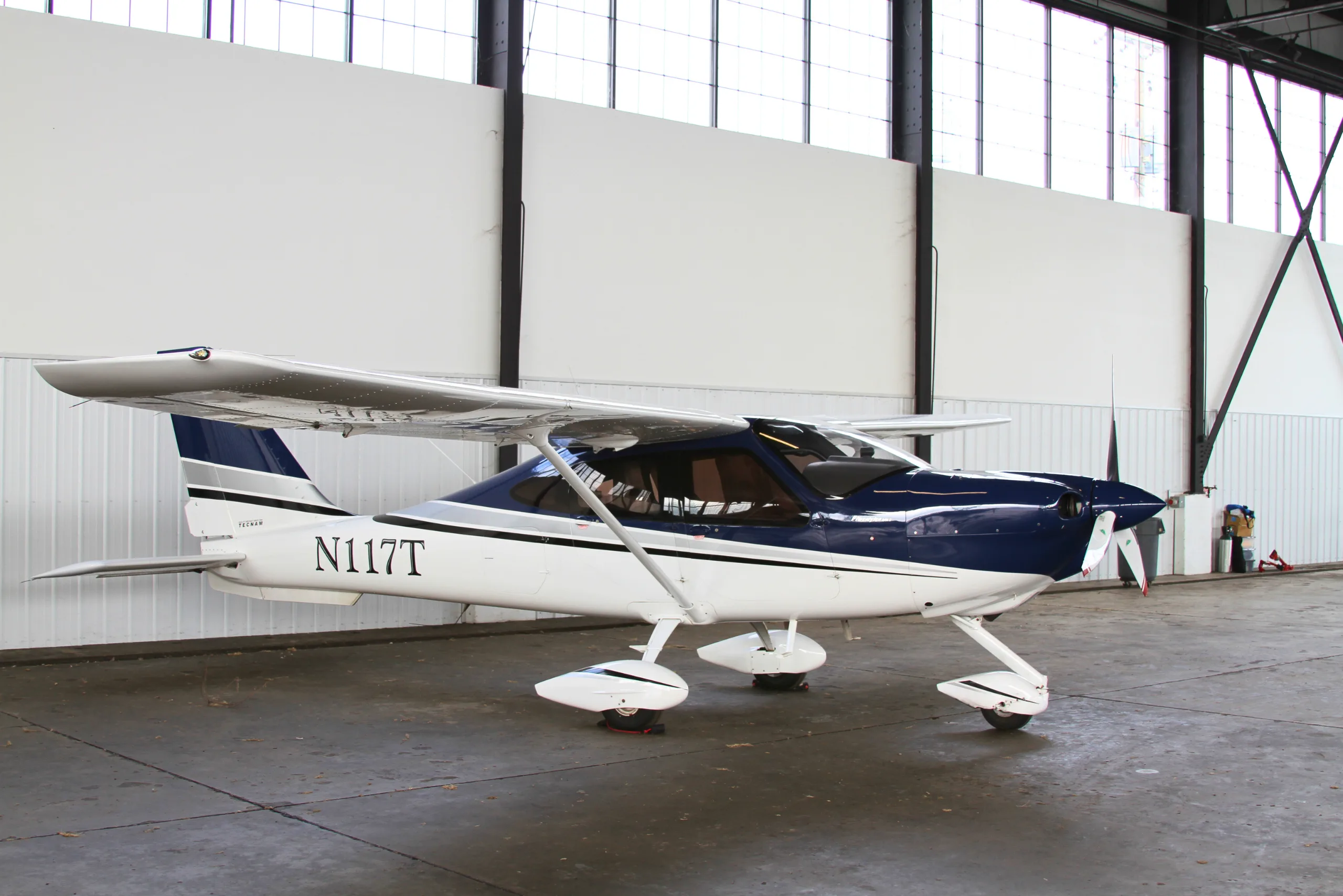 A white and blue light aircraft parked inside a hangar.