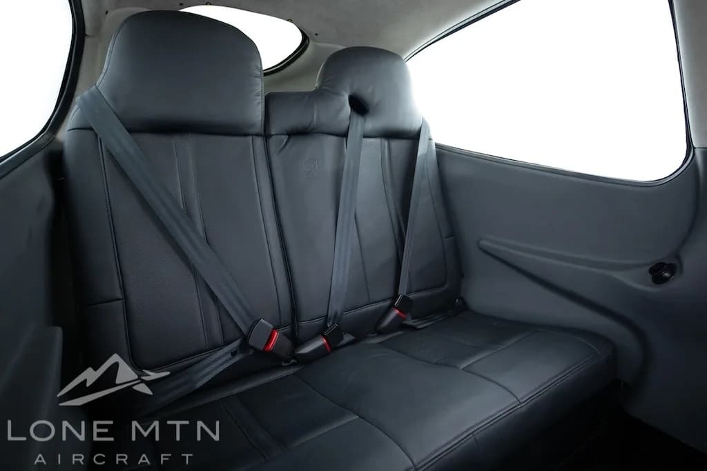 The black leather rear seats of a Cirrus SR22 aircraft cabin with seatbelts fastened.