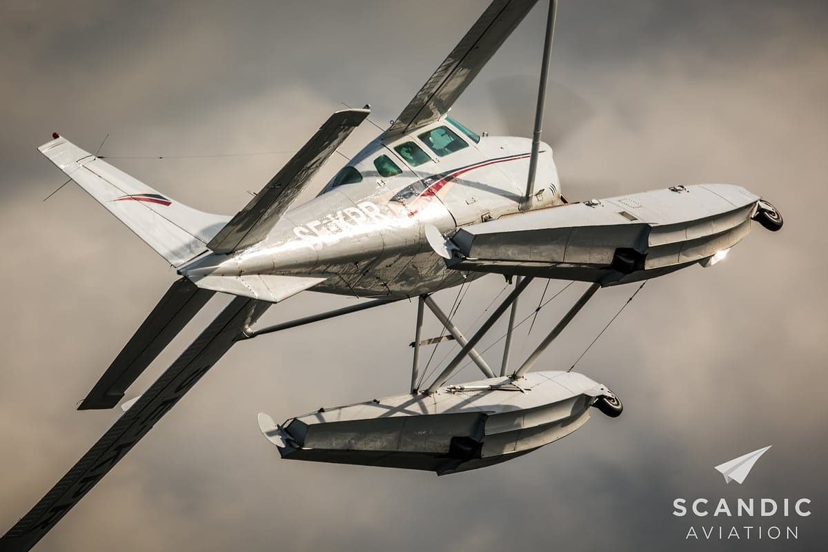 White and maroon floatplane in flight.