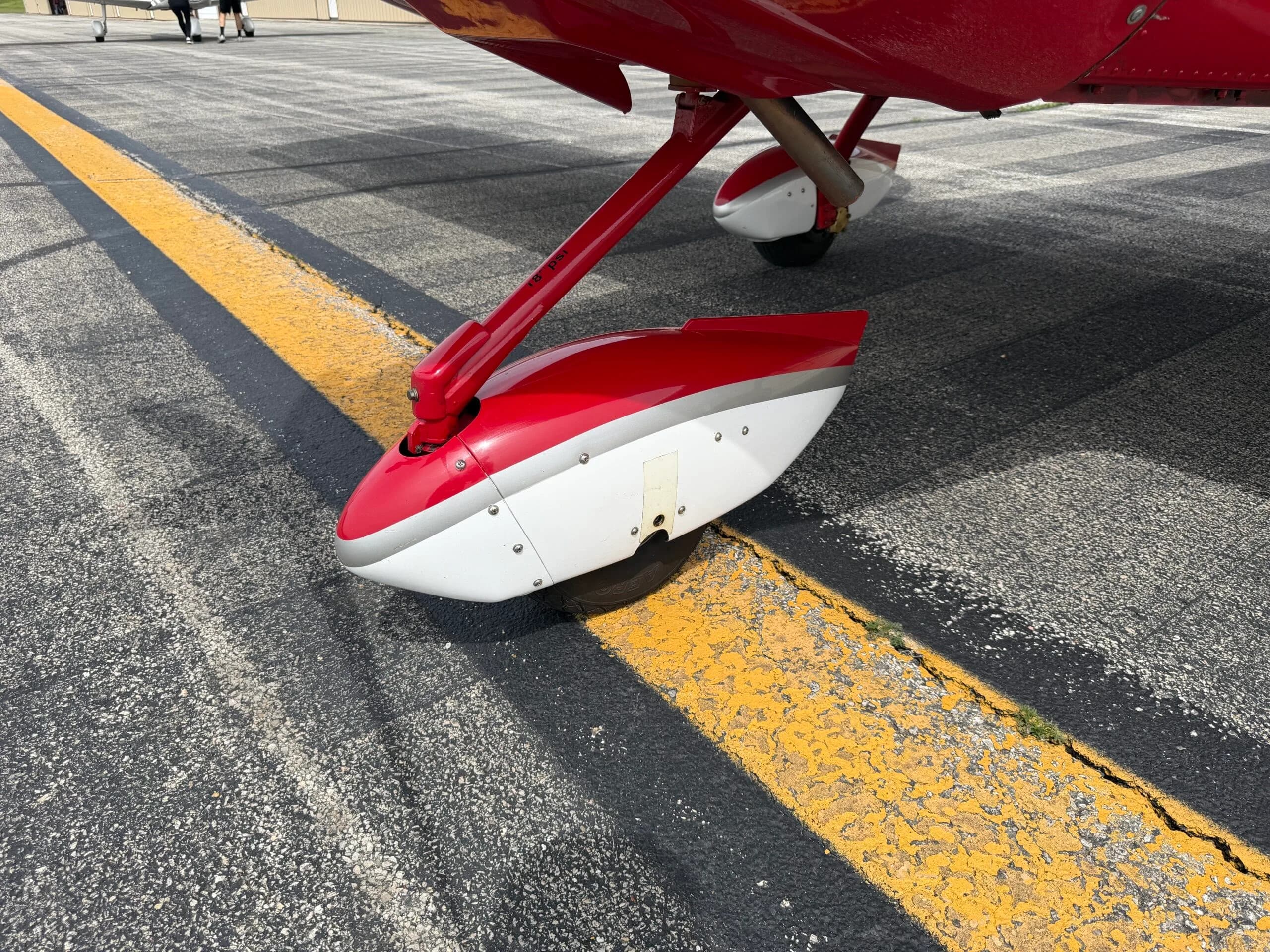 Close-up view of the red and white main landing gear of the SportCruiser aircraft on the tarmac.